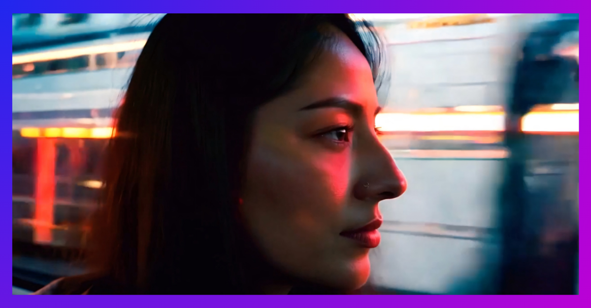 Profile of woman in motion, city lights blur past. Her face illuminated by red glow, pensive expression.